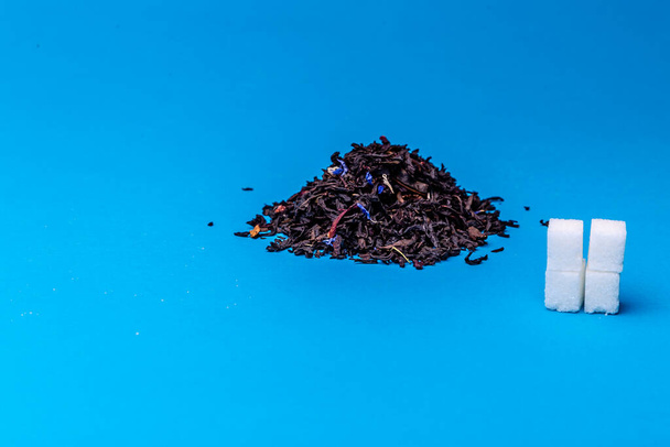 купа чорного чаю і кубиків білого цукру на синьому фоні
 - Фото, зображення