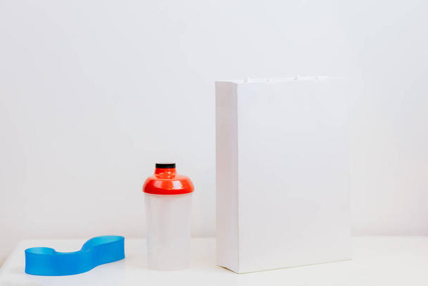 макет белого бумажного пакета и фитнес-аксессуары - Фото, изображение