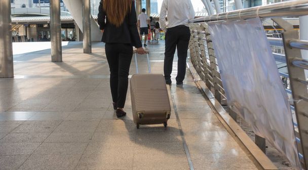 туристична бізнес-леді тягне сумку валізи, що йде вздовж міста
 - Фото, зображення