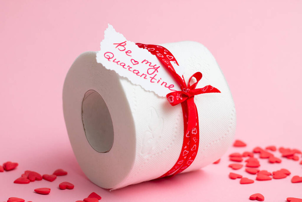 Rolka papieru toaletowego jako prezent Walentynki z notatką Be My Quarantine, obok czerwonych serc na różowym tle - Zdjęcie, obraz