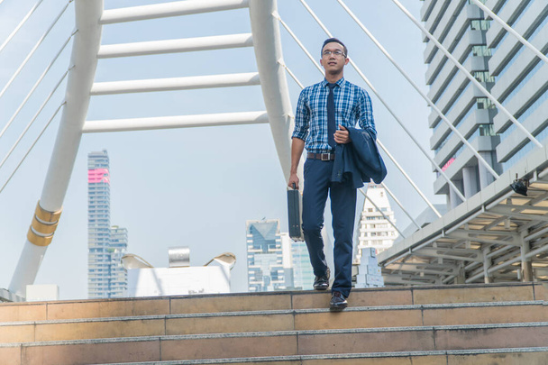 Молодий бізнесмен стоїть на сходах міста і дивиться вперед
. - Фото, зображення