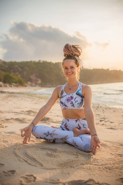 Kaunis nainen joogaamassa rannalla. Istun Padmasanassa, Lotus Pose. Kädet gyan mudrassa. Positiivista energiaa. Terveellisen elämän käsite. Joogaretriitti. Thomas Beach, Bali, Indonesia - Valokuva, kuva