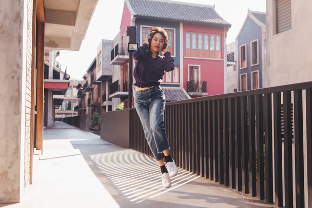 Happy young asian woman listening to music and having fun with headphones on the street. - 写真・画像
