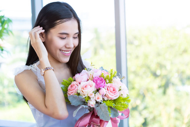 Valentine's day concept, Happy of smiling Asian young female sitting at a table food holding a bouquet of roses at in the restaurant background - Photo, Image