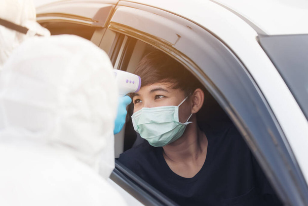 Mujer asiática Drive Thru Covid-19 Pruebas con el personal médico del PPE, prueba COVID temporal mientras se registra en los coches - Foto, imagen