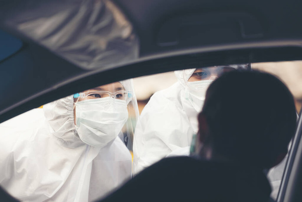 Aziatische vrouw rijden Thru Covid-19 testen met PPE medisch personeel, COVID testen van de temperatuur tijdens het controleren van auto 's - Foto, afbeelding