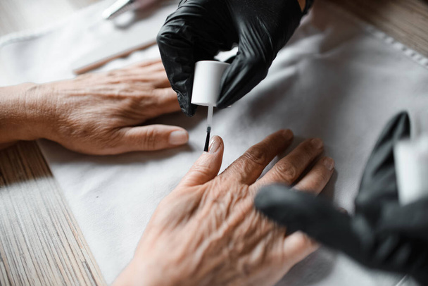 Manicurist paints a woman's nails with varnish, close-up. Nail care. Beauty salon concept - Photo, image