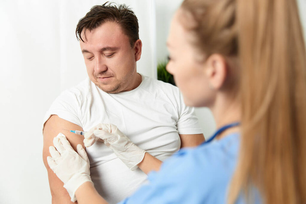 a doctor gives an injection to a mans hand health vaccination - Zdjęcie, obraz