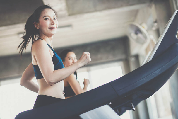 Attraktive asiatische Sportlerinnen laufen mit Freundin auf Laufband im Fitnessstudio gesunde Frauen - Foto, Bild