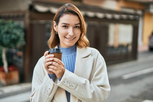 Jeune femme hispanique souriant heureux boire emporter café à la ville - Photo, image