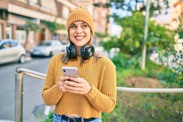 Young blonde woman using smartphone and headphones at the city. - Fotoğraf, Görsel