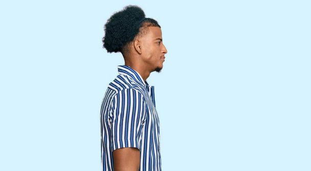 Afrykański Amerykanin z afro włosy noszenie ubrań casual patrząc na bok, relaks profil pozować z naturalną twarz z pewnym uśmiechem.  - Zdjęcie, obraz