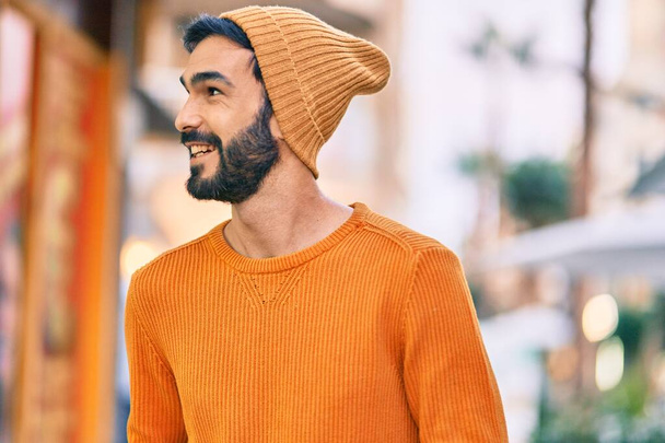 Mladý hispánec v zimním stylu se šťastně usmívá ve městě. - Fotografie, Obrázek