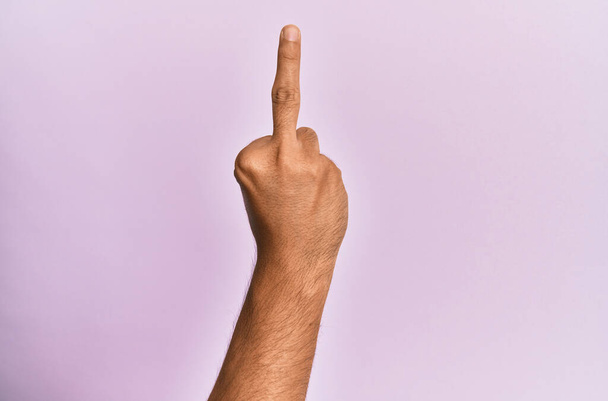 Arm und Hand eines kaukasischen jungen Mannes über rosa isoliertem Hintergrund, der eine provokante und unhöfliche Geste zeigt und dabei Fick-dich-Symbol mit dem Mittelfinger zeigt  - Foto, Bild
