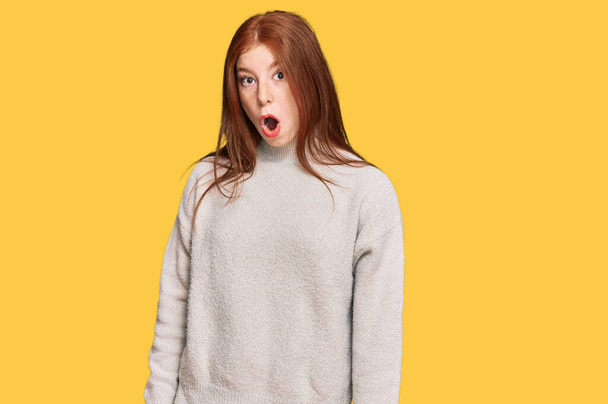 Young read head woman wearing casual winter sweater scared and amazed with open mouth for surprise, disbelief face  - Zdjęcie, obraz