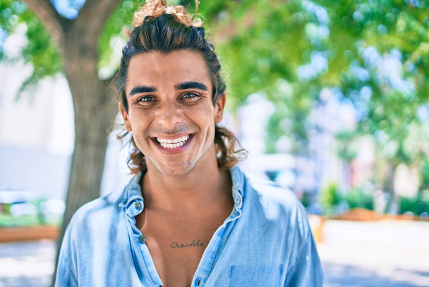 Jovem homem hispânico bonito sorrindo feliz andando na rua da cidade - Foto, Imagem