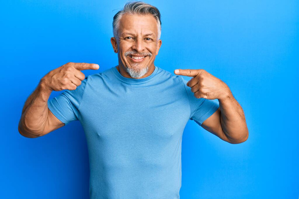 Middle age grey-haired man wearing casual clothes smiling cheerful showing and pointing with fingers teeth and mouth. dental health concept.  - Fotó, kép