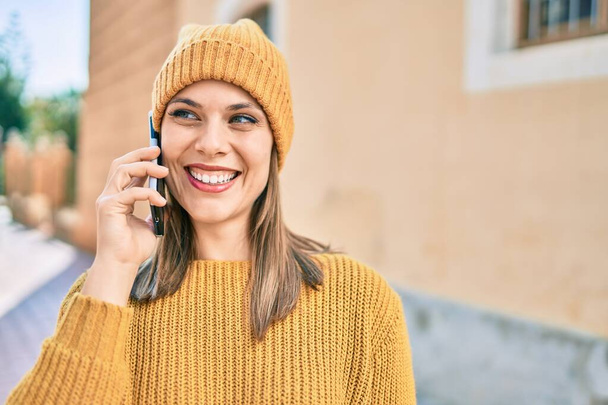 Mujer rubia joven sonriendo feliz usando el teléfono inteligente en la ciudad. - Foto, imagen