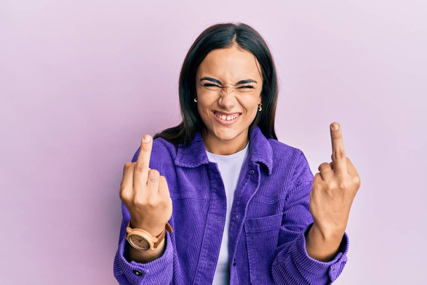 Young brunette woman wearing casual clothes showing middle finger doing fuck you bad expression, provocation and rude attitude. screaming excited  - Fotoğraf, Görsel