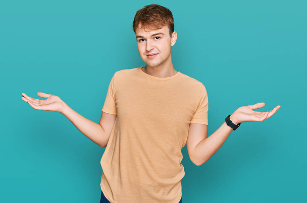 Giovane uomo caucasico indossa abiti casual sorridente mostrando entrambe le mani palme aperte, presentando e pubblicizzando confronto ed equilibrio  - Foto, immagini