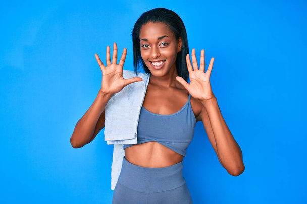 Joven mujer afroamericana usando ropa deportiva mostrando y señalando hacia arriba con los dedos número diez mientras sonríe confiado y feliz.  - Foto, Imagen