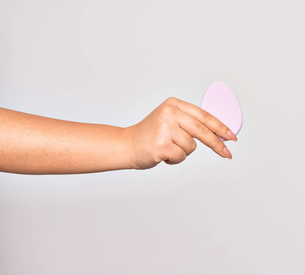 Рука білої жінки, що тримає рожеву губку для макіяжу над ізольованим білим тлом
 - Фото, зображення