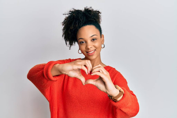 Jong Afrikaans-Amerikaans meisje met casual kleren die glimlachen van liefde en hartsymbool vormen met handen. romantisch concept.  - Foto, afbeelding