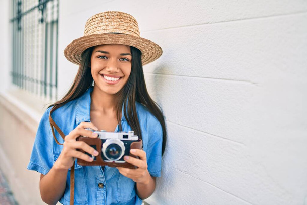 Tatildeki genç Latin turist kız şehirde klasik kamera kullanarak mutlu mesut gülümsüyor.. - Fotoğraf, Görsel