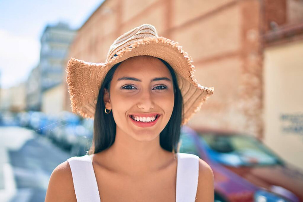 Νεαρή Λατίνα κοπέλα που φοράει καλοκαιρινό στυλ και χαμογελά ευτυχισμένη στο δρόμο της πόλης. - Φωτογραφία, εικόνα