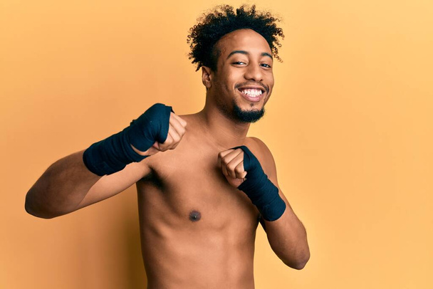Jonge Afro-Amerikaanse man met baard die boksbescherming draagt glimlachend met een blije en coole glimlach op zijn gezicht. tanden tonen.  - Foto, afbeelding
