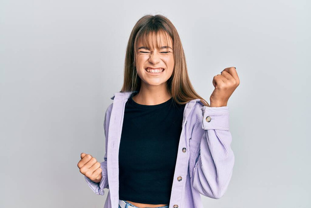 Adolescente caucasiano menina vestindo roupas casuais comemorando surpreso e surpreso com o sucesso com os braços levantados e os olhos fechados  - Foto, Imagem