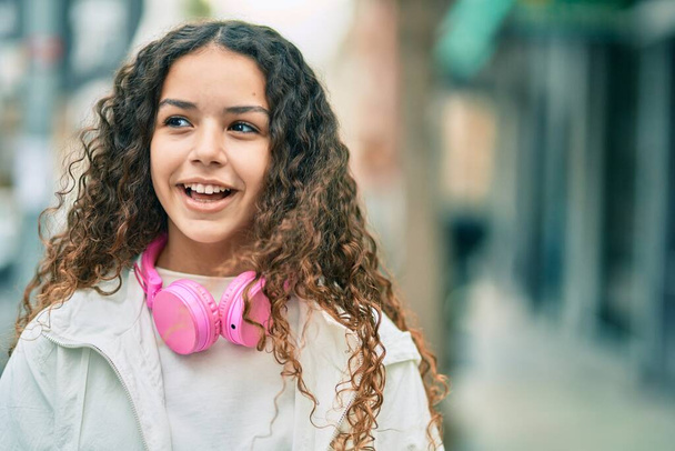 Hispanic child girl smiling happy using headphones at the city. - Foto, imagen