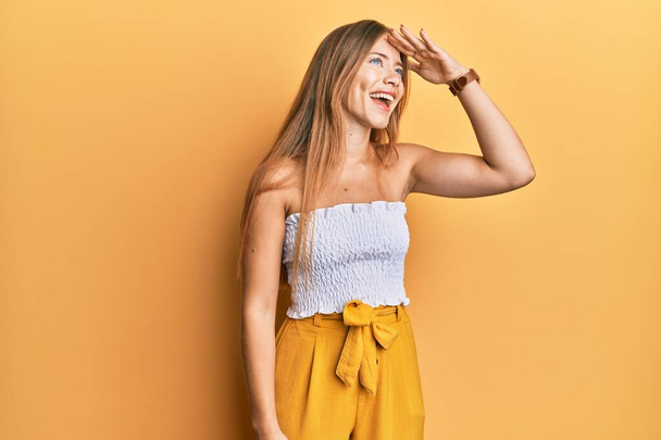 Beautiful young blonde woman wearing casual summer clothes very happy and smiling looking far away with hand over head. searching concept.  - Photo, Image