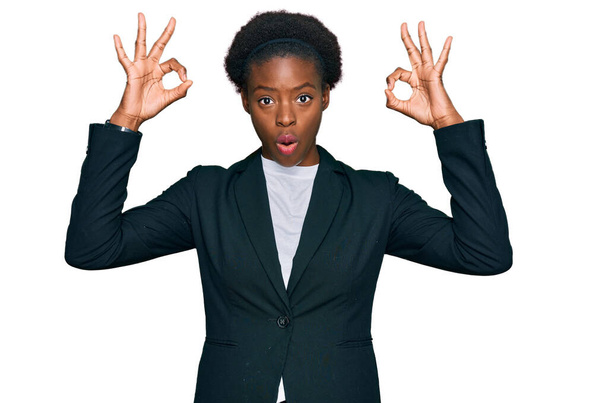 Jeune fille afro-américaine portant des vêtements de travail à l'air surpris et choqué de faire ok symbole d'approbation avec les doigts. expression folle  - Photo, image