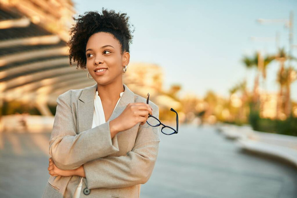 Young african american businesswoman smiling happy holding glasses at the city. - Photo, Image