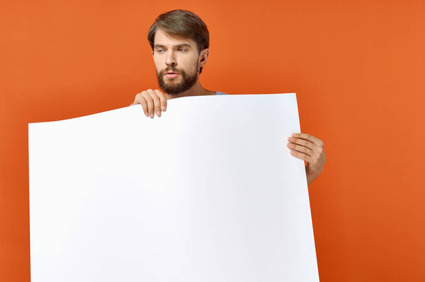парень с белой бумагой на оранжевом фоне Плакат рекламный знак - Фото, изображение