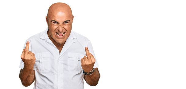 Mature middle east man with mustache wearing casual white shirt showing middle finger doing fuck you bad expression, provocation and rude attitude. screaming excited  - Photo, Image