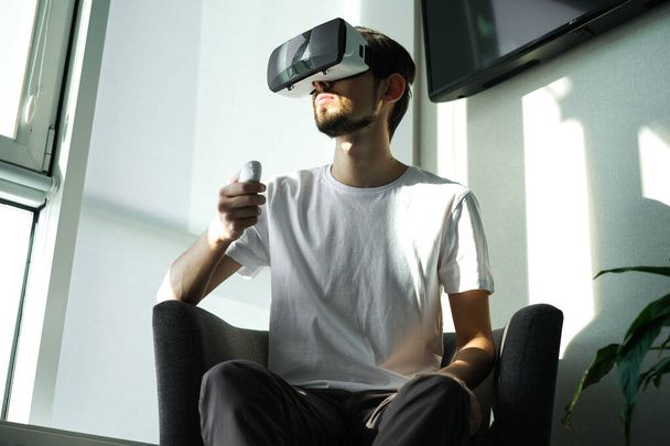 Young man vigorously plays virtual reality video game with control panel. man plays video games. Time relax. Joyfull weekend. Concentrated on the video game. Winning the game, gambling. Multiplayer ga - Photo, Image