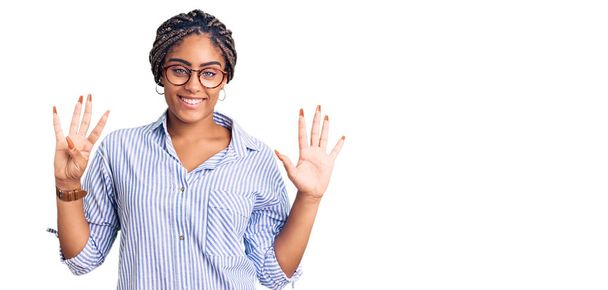 Young african american woman with braids wearing casual clothes and glasses showing and pointing up with fingers number nine while smiling confident and happy.  - Photo, Image