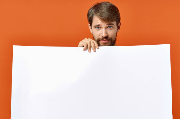 bearded man with poster in hand on orange background Copy Space - Zdjęcie, obraz