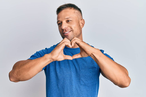 Handsome muscle man wearing casual clothes smiling in love doing heart symbol shape with hands. romantic concept.  - Fotoğraf, Görsel