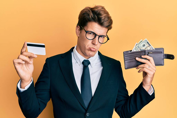 Handsome caucasian business man holding credit card and wallet with dollars depressed and worry for distress, crying angry and afraid. sad expression.  - Foto, Imagem