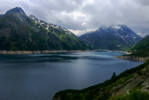 wunderschöner See aus einem Wasserkraftwerk in den Bergen aus Österreich mit Regenwolken - Foto, Bild