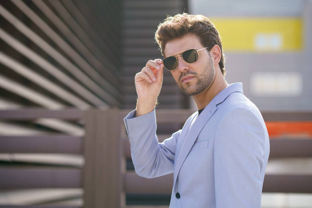 Young handsome man wearing sunglasses in urban background - Zdjęcie, obraz