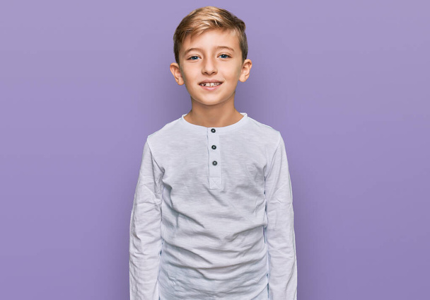 Kleiner kaukasischer Junge in lässiger Kleidung mit einem fröhlichen und kühlen Lächeln im Gesicht. Glück gehabt.  - Foto, Bild