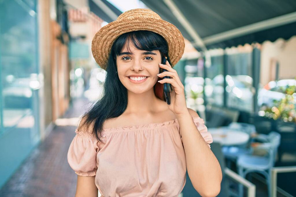 Giovane ragazza turistica ispanica indossa lo stile estivo parlando sullo smartphone in città. - Foto, immagini