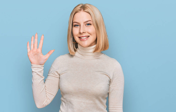 Jeune femme blonde portant des vêtements décontractés montrant et pointant vers le haut avec les doigts numéro cinq tout en souriant confiant et heureux.  - Photo, image