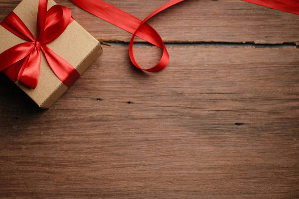 Szelektív fókusz ajándék doboz piros szalaggal és szerelem alakú papír felett rusztikus fa asztal, felső nézet lapos feküdt. - Fotó, kép
