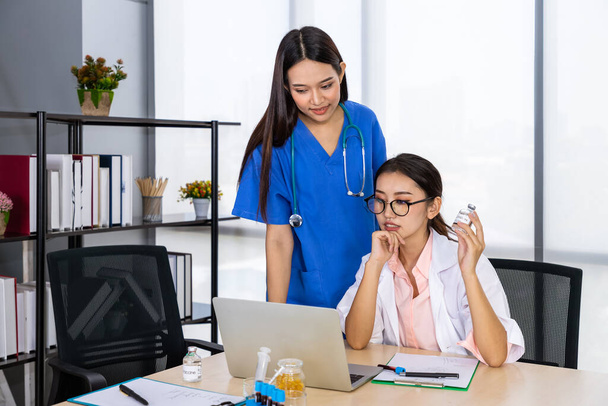 Two Asian female medical doctor sitting at desk and meeting discussion about vaccine with laptop computer - Photo, Image
