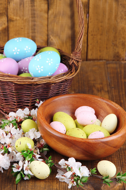 Composition avec branches fleuries et oeufs de Pâques dans un bol en bois, panier en osier sur fond en bois
 - Photo, image